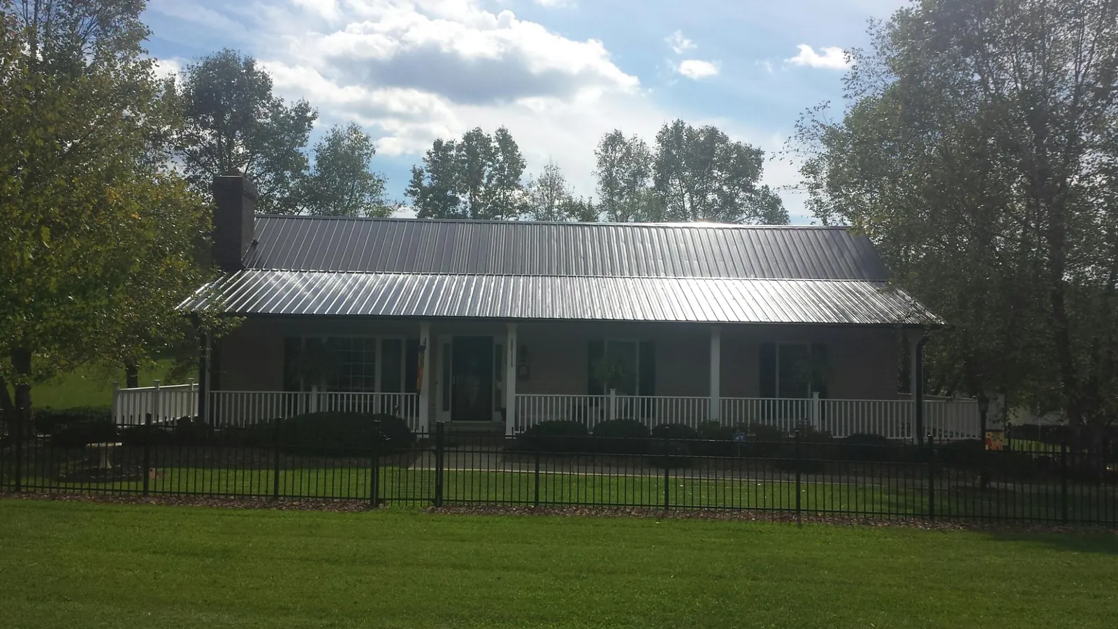 Gray metal roof on a brick ranch with a full width front porch — Gutter Guard Installation work by our crew in Smyrna